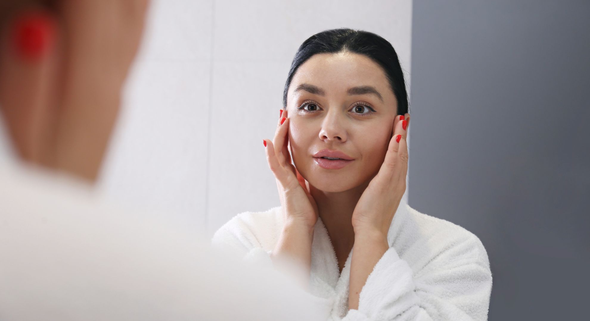 IPL skin texture and tone - woman with dark hair and red nails looking at herself