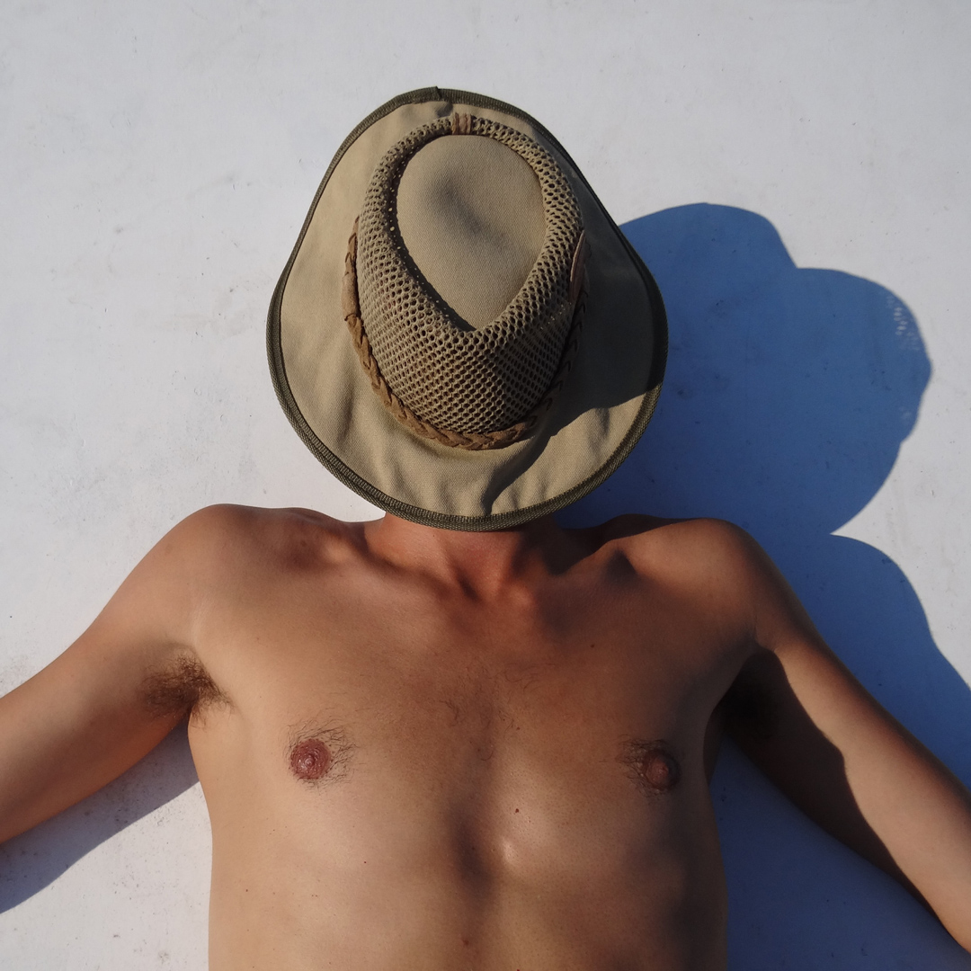 Dermatologists Recommend Heliocare for Year Round Sun Defense -- many laying out in the sun with hat over face.